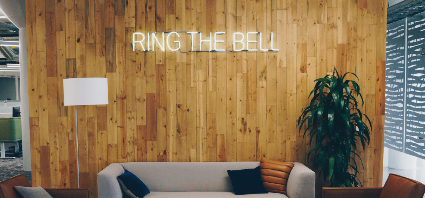 A room in the Premier Nutrition office that has a neon sign that says Ring The Bell.