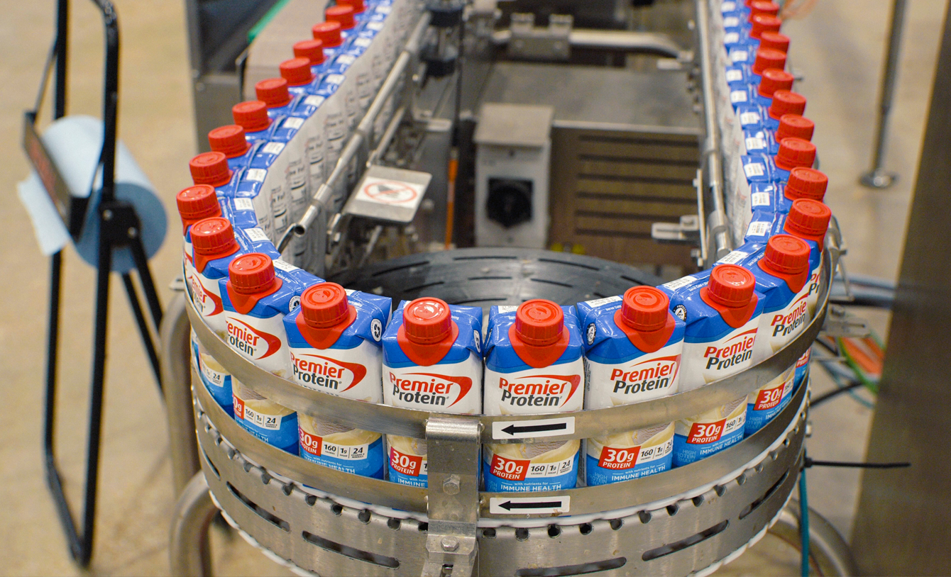 A mechanical assembly line showing Premier Nutrition tetra bottles being manufactured.